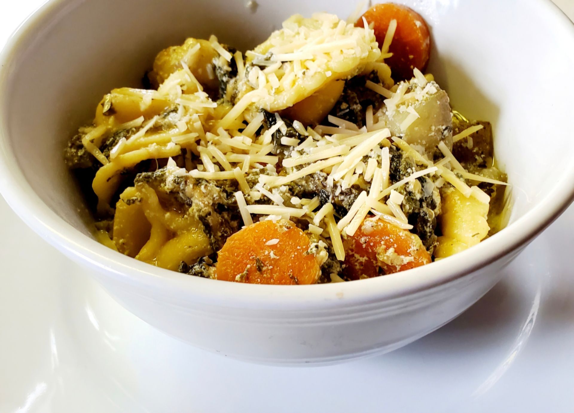 Bowl of pasta with vegetables and grated cheese.