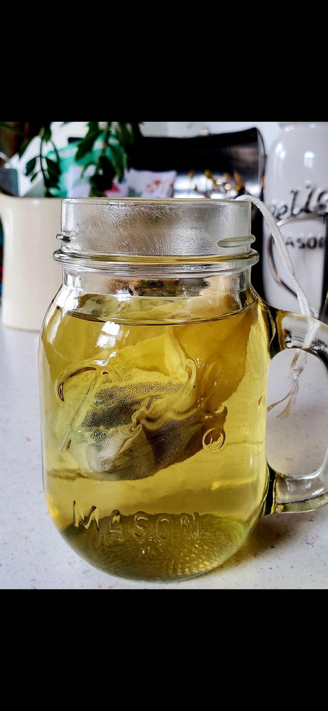 Mason jar filled with yellow liquid, a tea bag submerged inside.