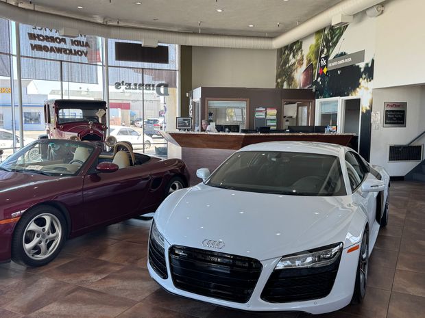 Silver Porsche in a garage, man opening door. | Dibble's Auto Center