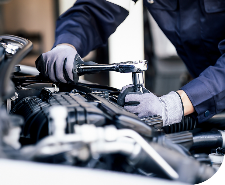 Mechanic in blue jumpsuit using a wrench on a car engine, wearing gray gloves - Dibble's Auto Center