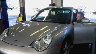Silver Porsche in a garage, man opening door. | Dibble's Auto Center