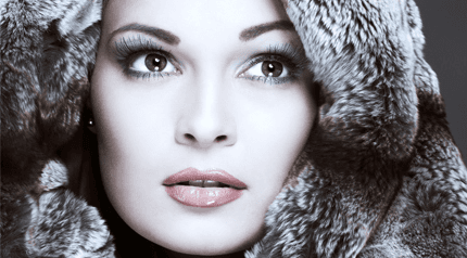 A lady with glossy lips and smokey eyes, wearing a fur hood