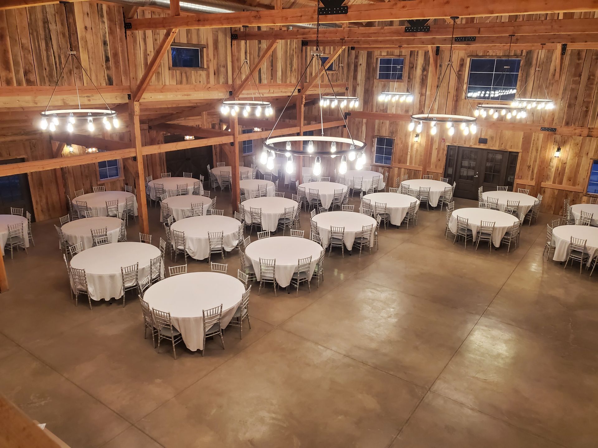 A large room filled with tables and chairs for a wedding reception.