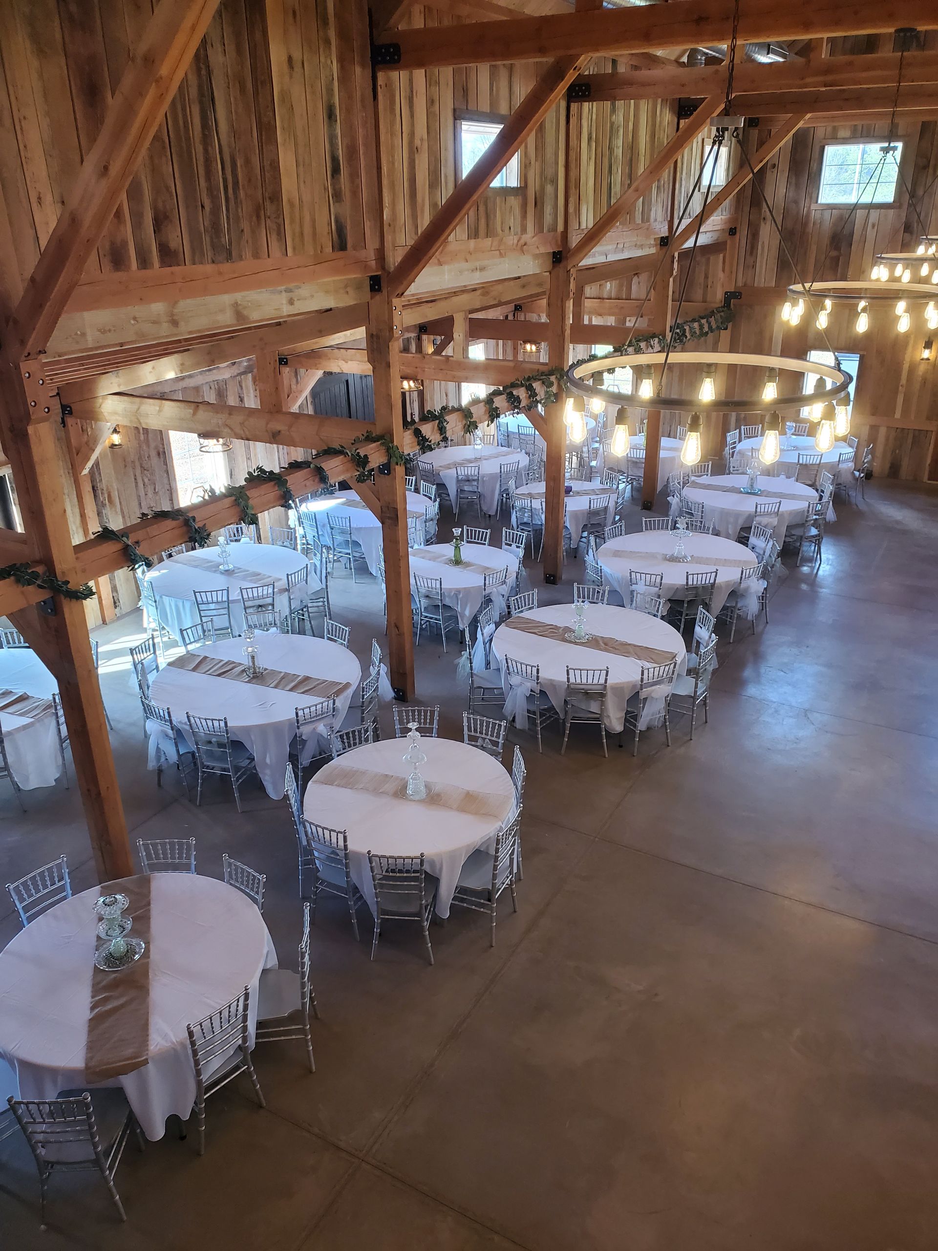 A large barn filled with tables and chairs for a wedding reception.