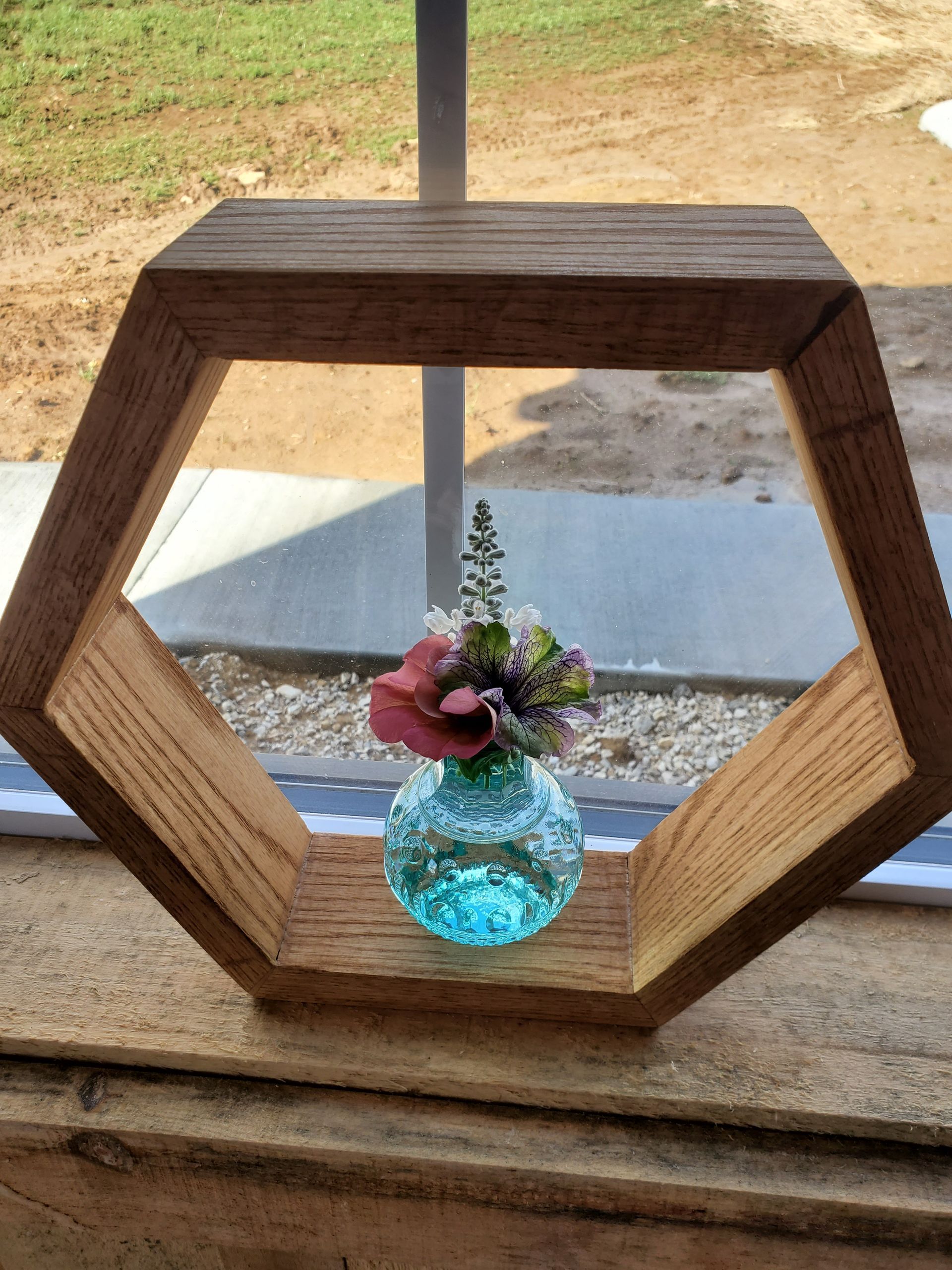 A vase with flowers in it is sitting on a wooden shelf.