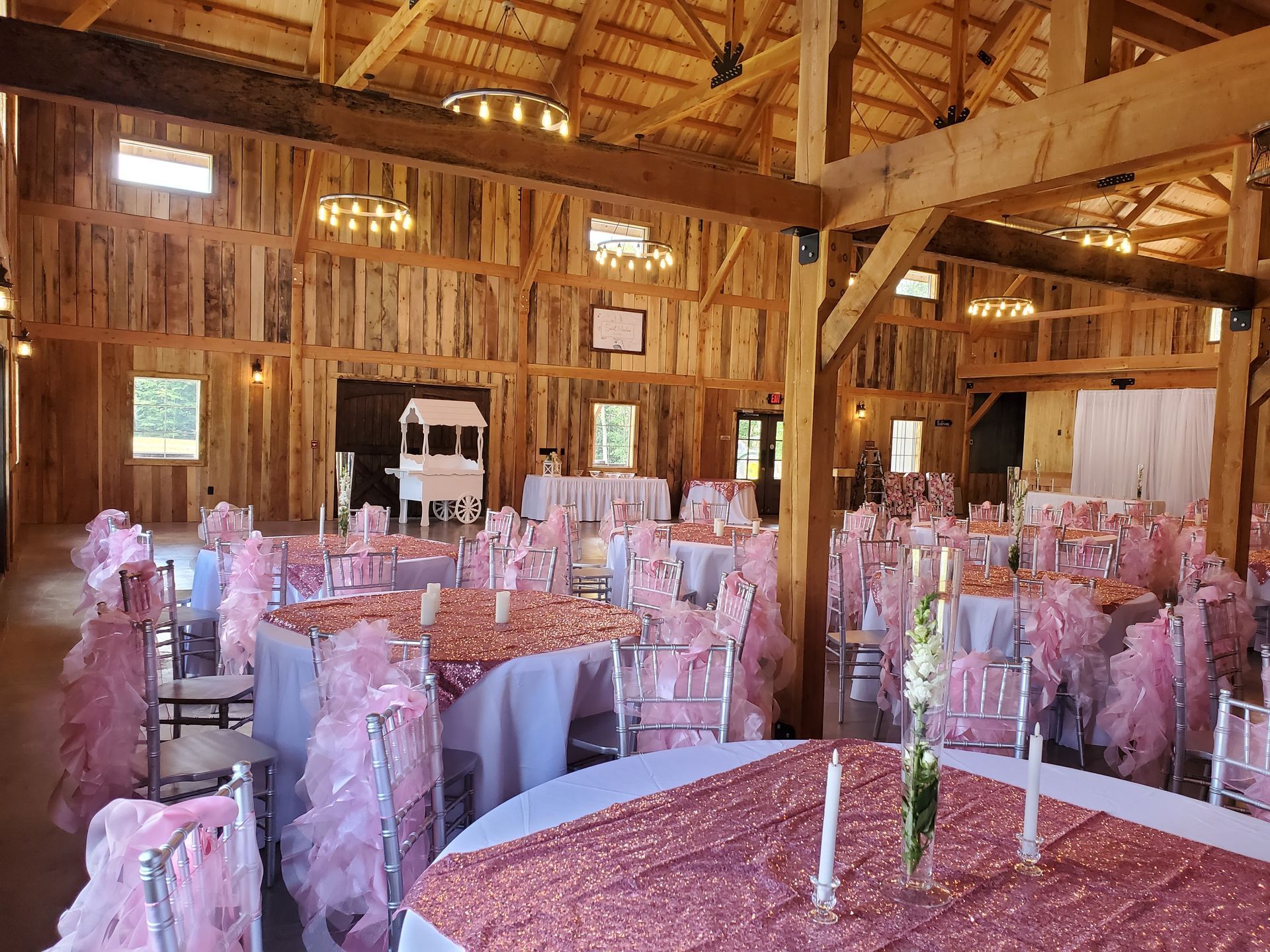 A large barn filled with tables and chairs decorated for a wedding reception.