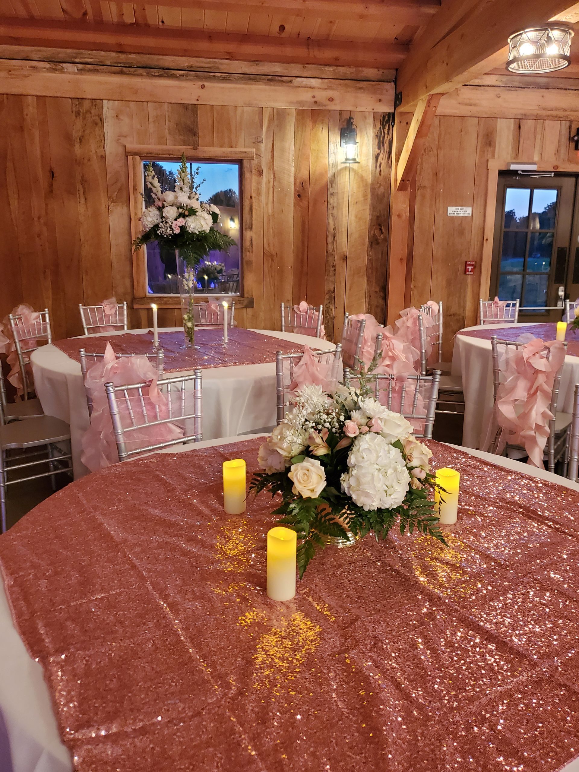 A table with a rose gold tablecloth and candles on it.