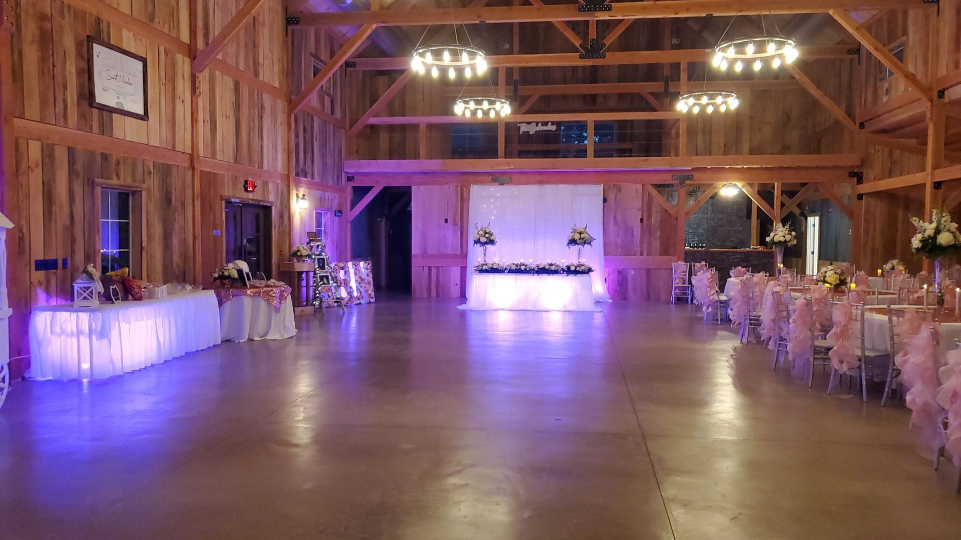 A large barn filled with tables and chairs for a wedding reception.