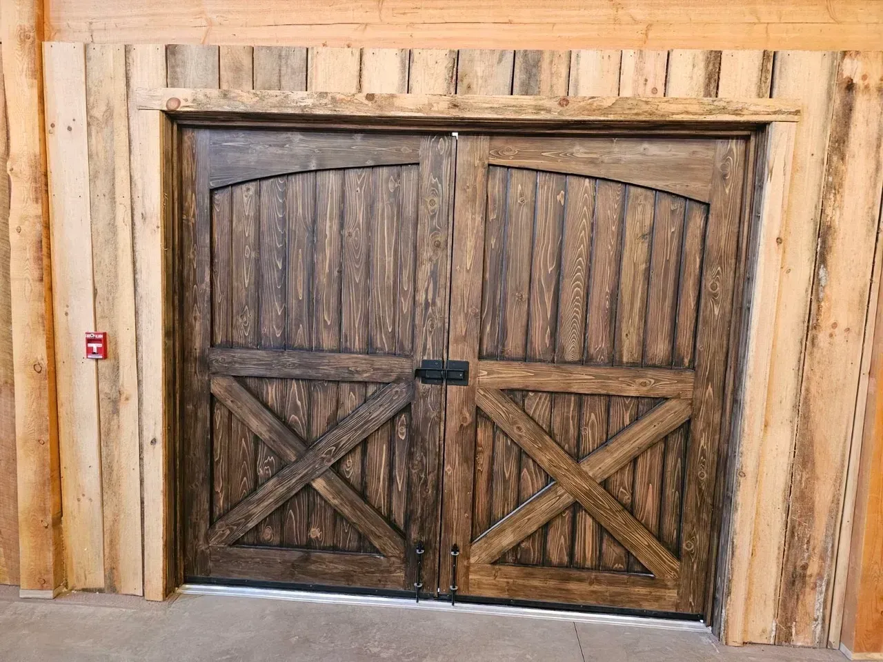A pair of wooden garage doors in a wooden building.