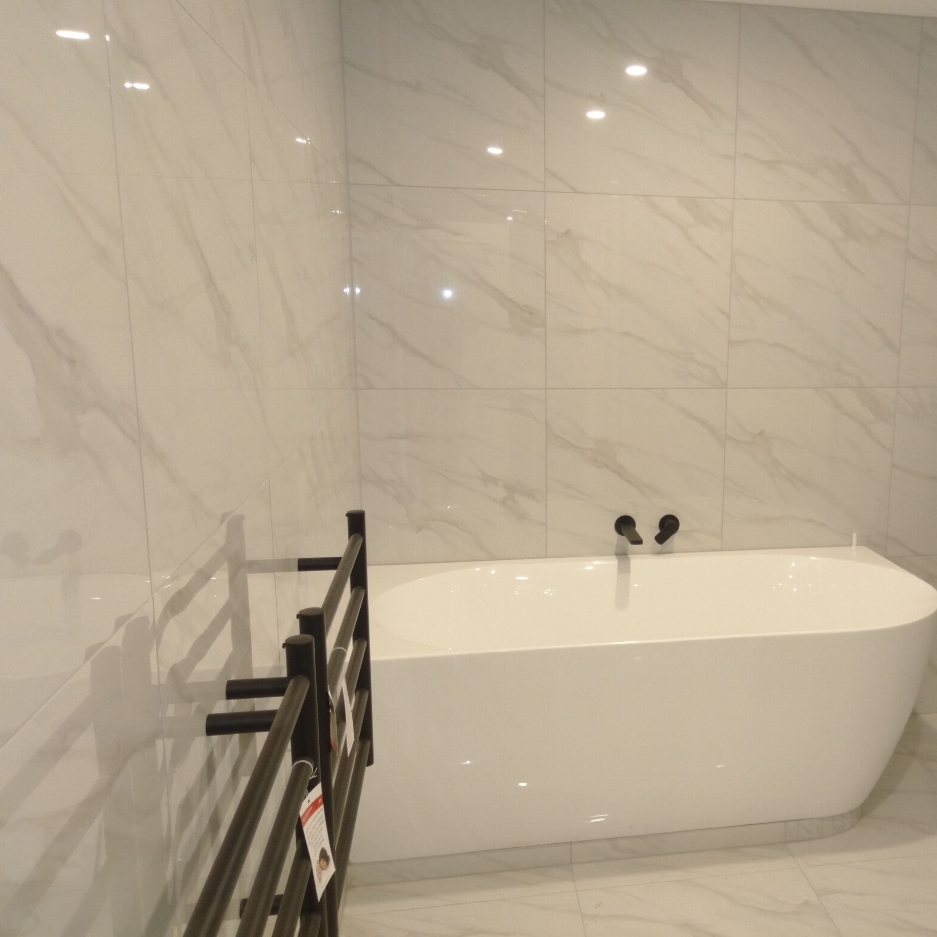 A bathroom with white tiles and a bathtub. Auckland Tilers