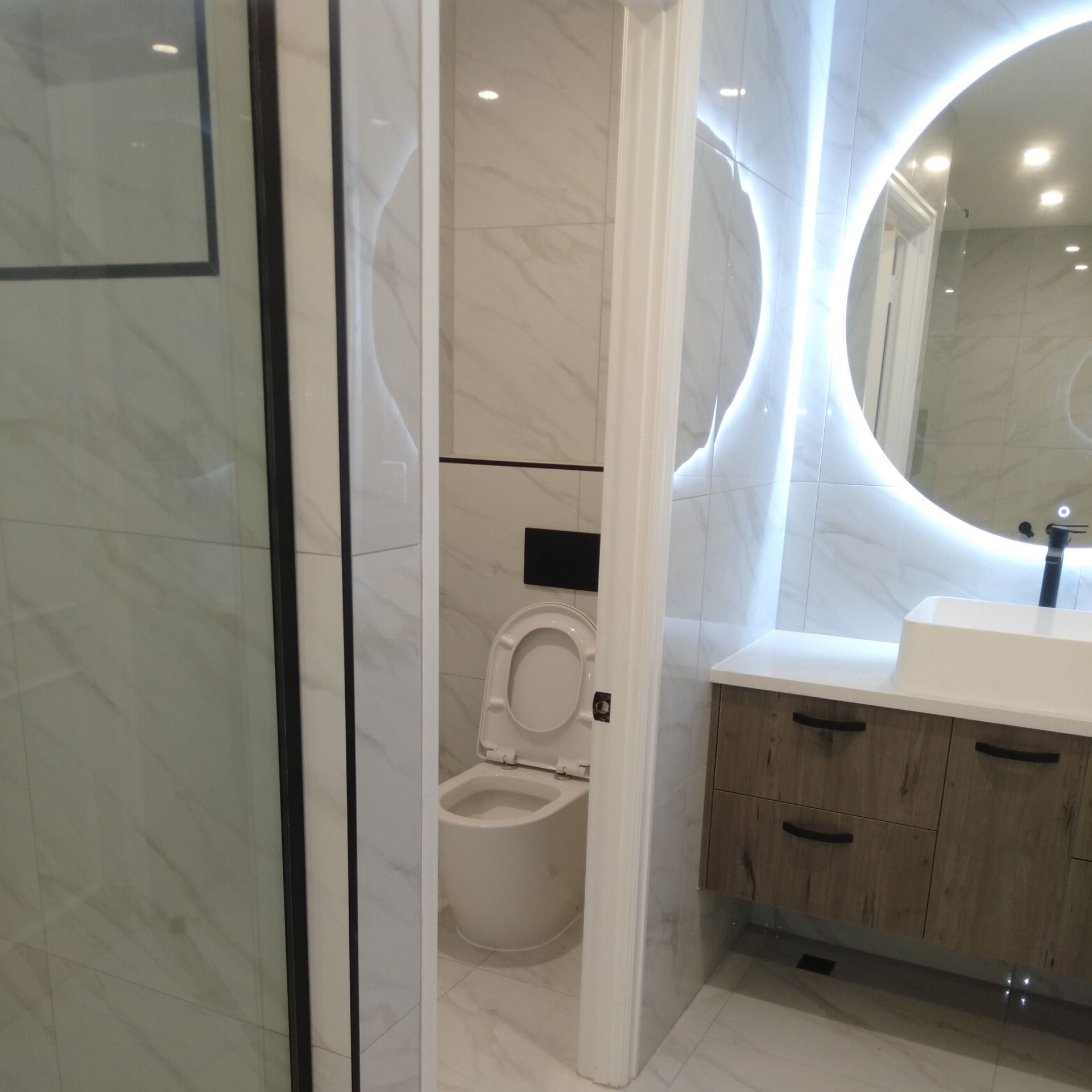 A bathroom with a toilet a sink and a mirror. Auckland Tilers
