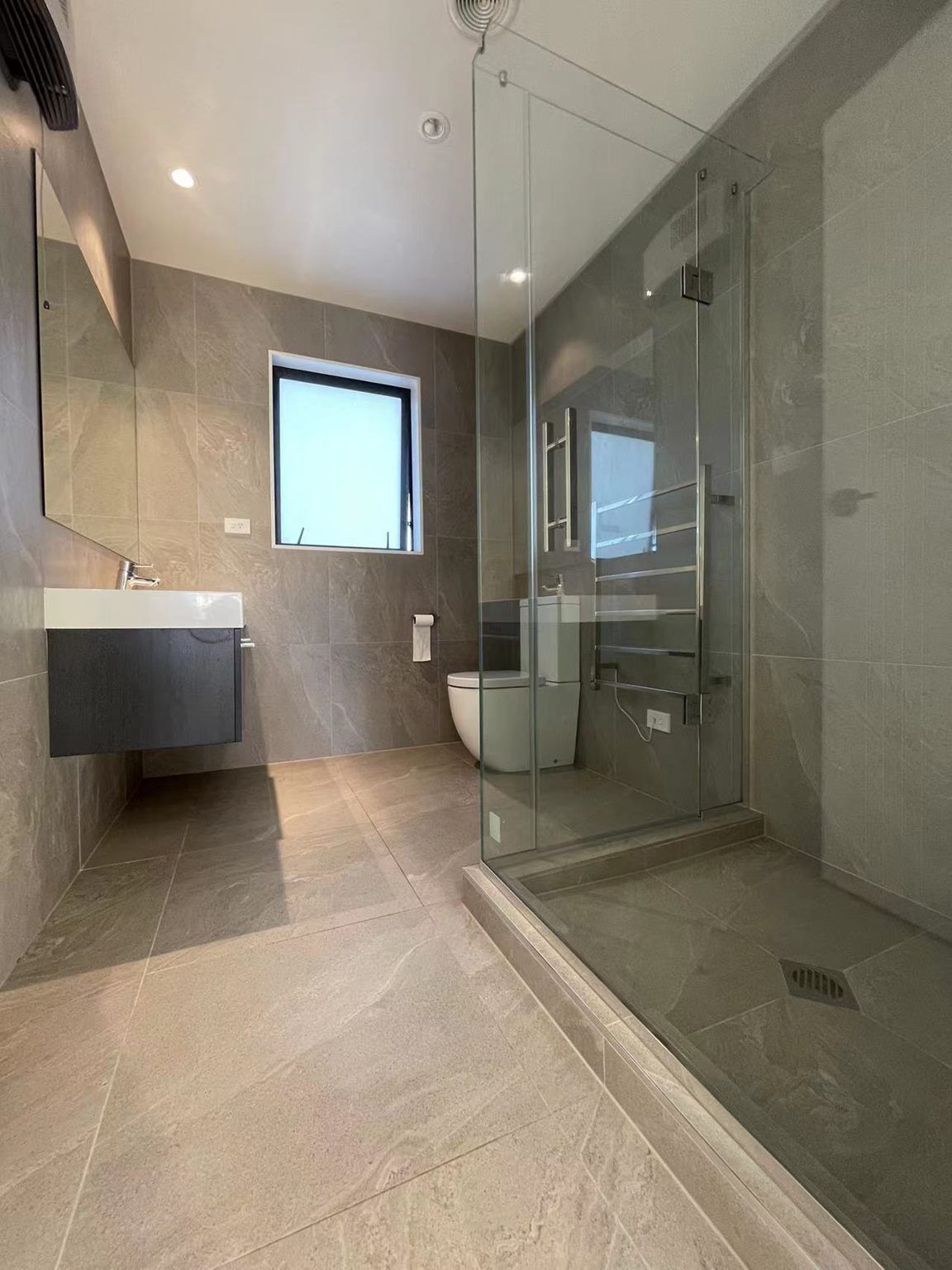 A bathroom with a toilet , sink and walk in shower. Auckland Tilers