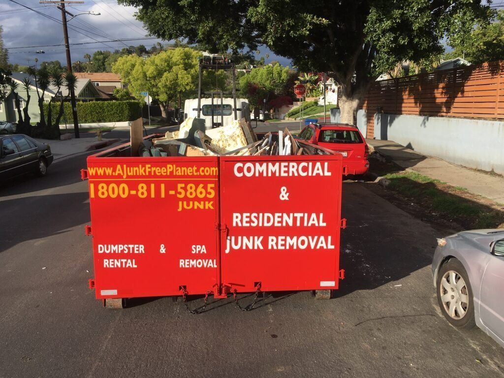 Red dumpster on street, filled with junk, advertisement for commercial & residential junk removal.