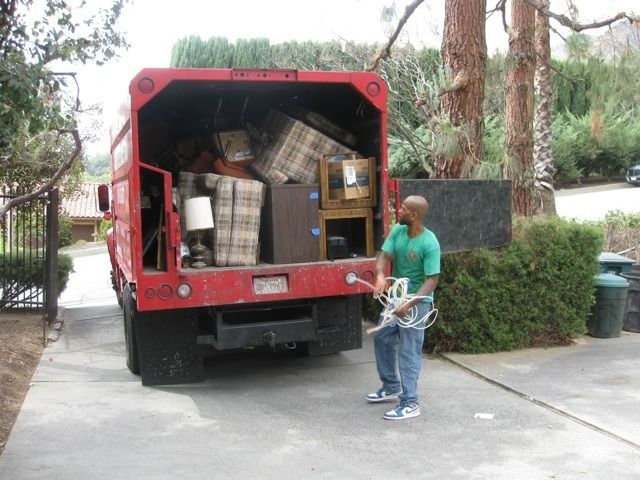 Man loading furniture into a red truck parked in a driveway.