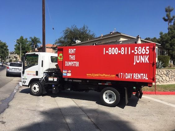 Red dumpster truck parked on a street; 