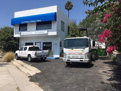 White building with blue awning and parked truck and pickup.