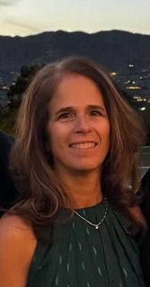 A man in a suit and blue shirt smiles for the camera