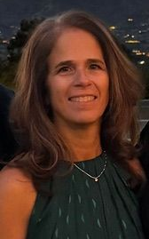 Smiling man in blue blazer and shirt, against a gray gradient background.