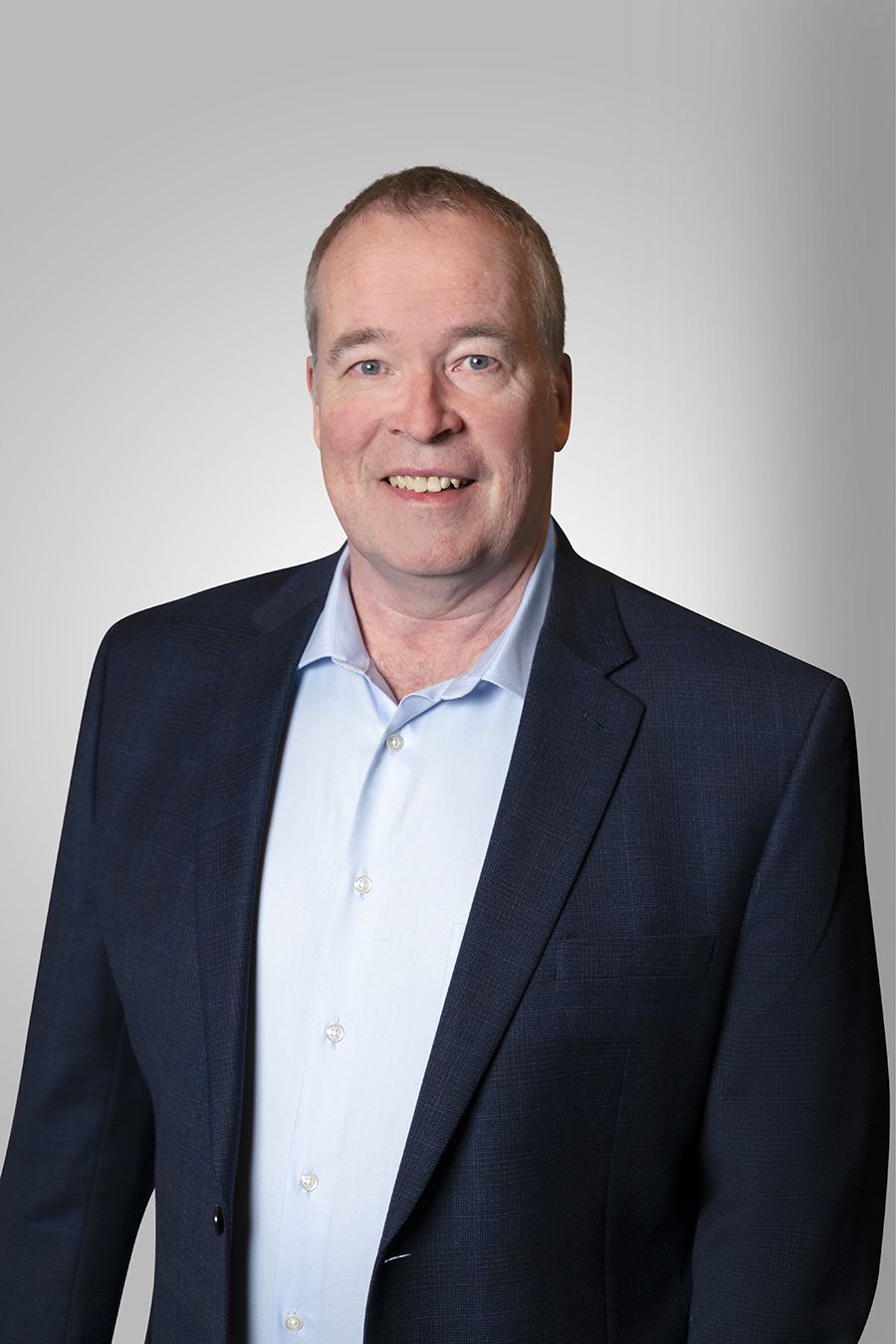 A man in a suit and blue shirt smiles for the camera