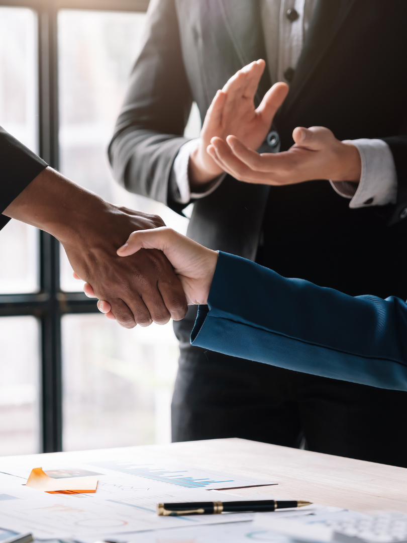 A man and a woman are shaking hands over a table.