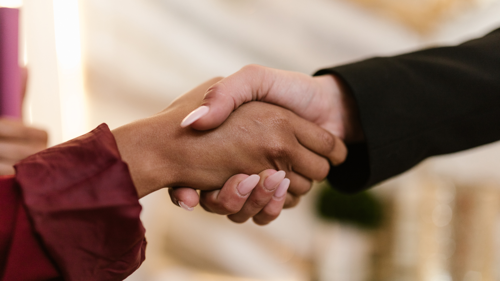 A man and a woman are shaking hands in a room.