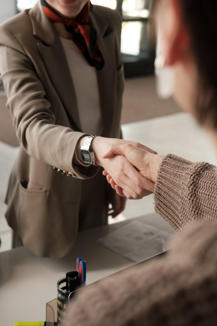 A man and a woman are shaking hands over a table.