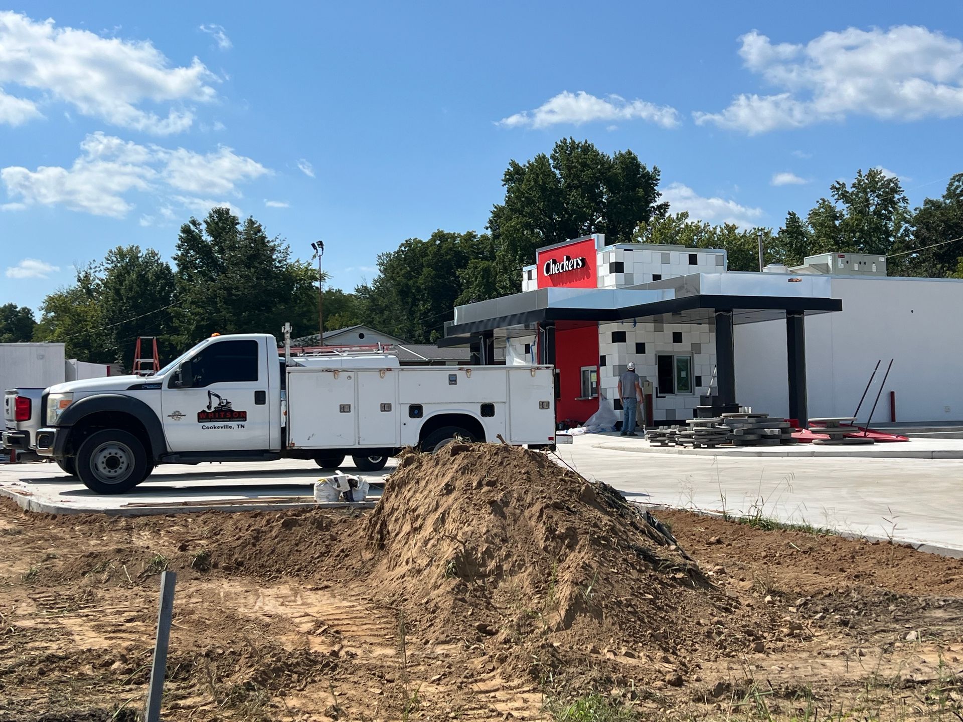 A white truck is parked in front of a building under construction.