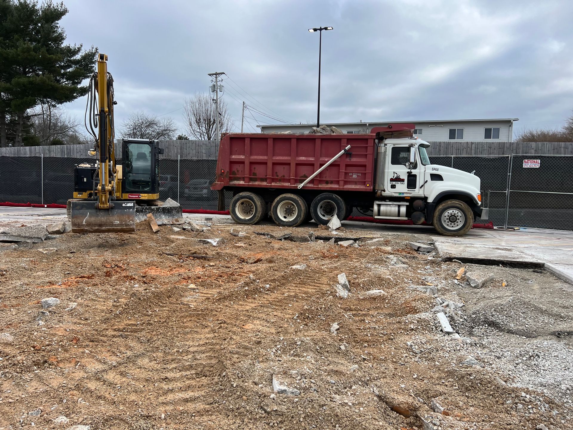 A dump truck is parked in a dirt field next to an excavator.