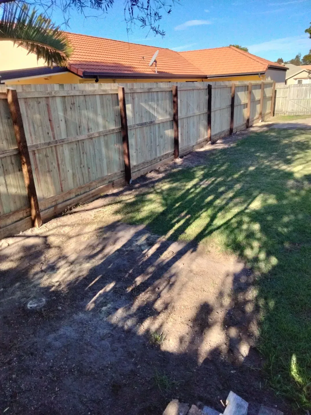 A Wooden Fence in a Shady Green Backyard — Tuff Fencing in Caboolture, QLD