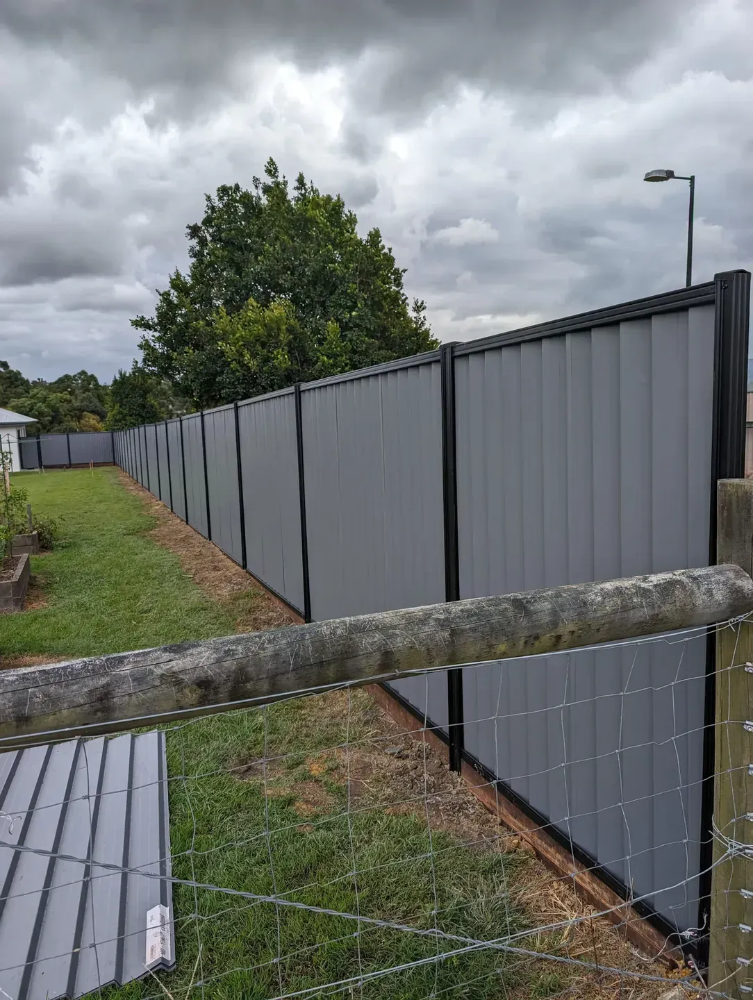 A Metal Fence in Backyard next to a Log Sleeper Fence — Tuff Fencing in Caboolture, QLD