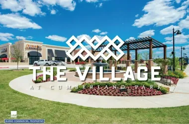 “The Village at Cuyahoga Falls” sign in a landscaped plaza under a blue sky