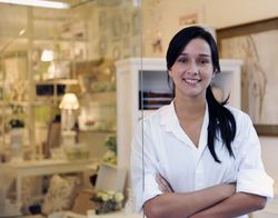 Smiling woman in a white shirt with arms crossed, standing in a bright laboratory or medical setting
