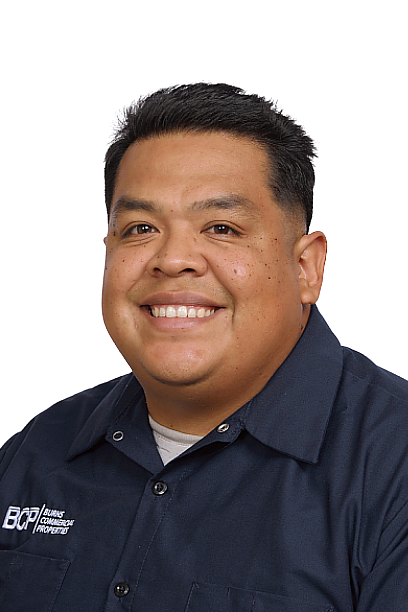 Smiling person in a navy button-up shirt against a white background