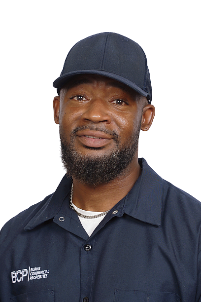 Man in a black cap and navy shirt, smiling against a white background.