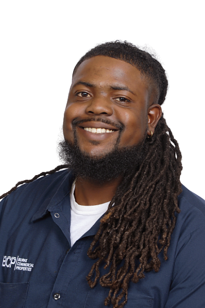Smiling person with long dreadlocks in a navy shirt against a white background