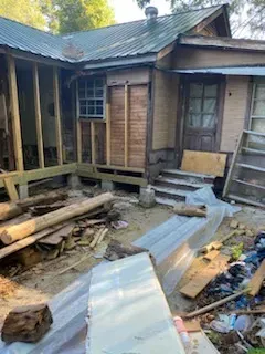 A house is being remodeled and there is a lot of trash in the yard.