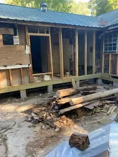 A house is being remodeled and a pile of wood is in front of it.