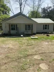 A white house is sitting on top of a lush green field.