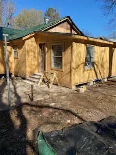 A small yellow house with a green roof is being built.