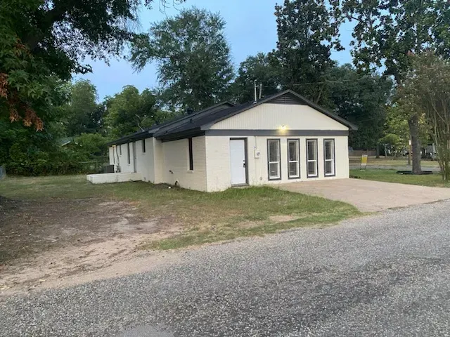 A white house with a lot of windows is sitting on the side of the road.