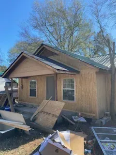 A small wooden house with a green roof is being built.