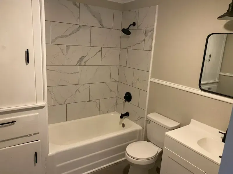 A bathroom with a bathtub , toilet , sink and mirror.