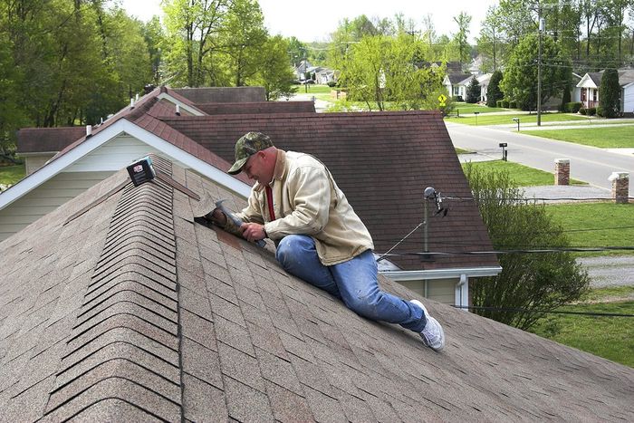 man sitting and installing roof tiles on the roof