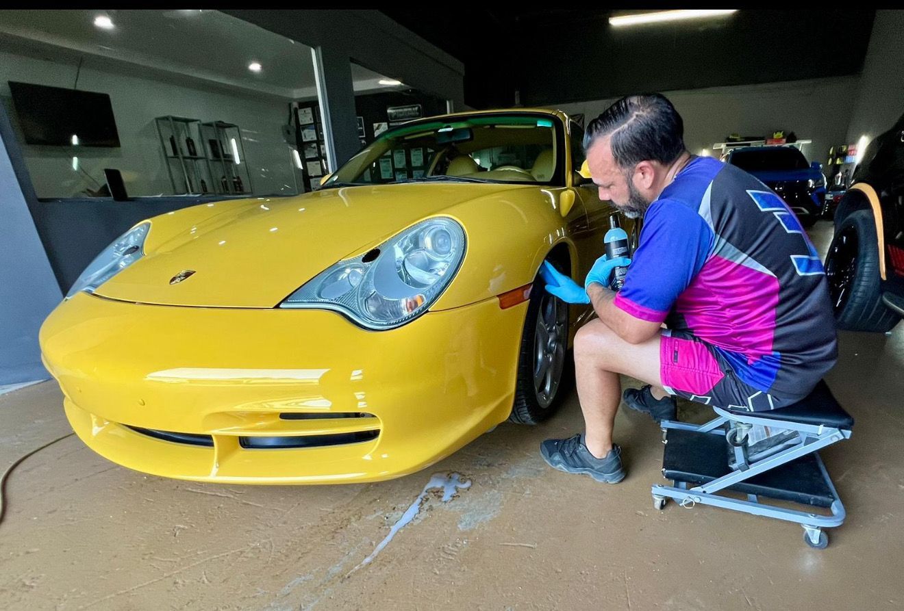 Man cleaning a car seat with a handheld extraction tool, inside the vehicle.