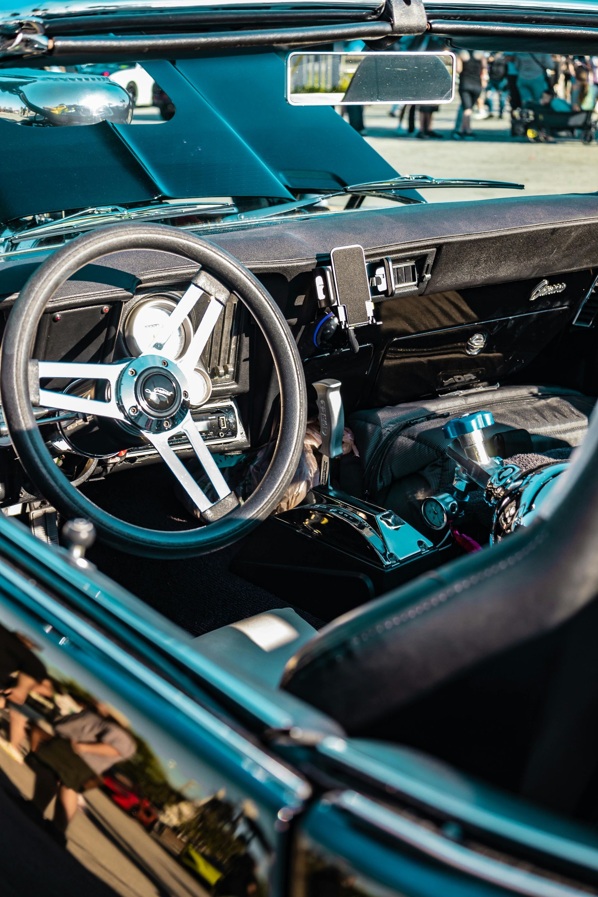 Black classic car interior, chrome steering wheel, exposed engine, convertible top.