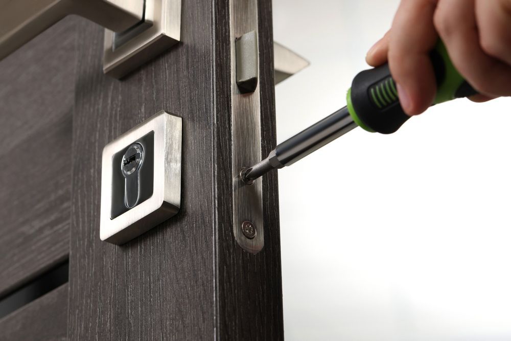 A person is repairing a door lock with a screwdriver — The Skeleton Key Locksmiths & Security in West Tamworth, NSW