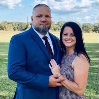 A man in a suit and tie is standing next to a woman in a dress.