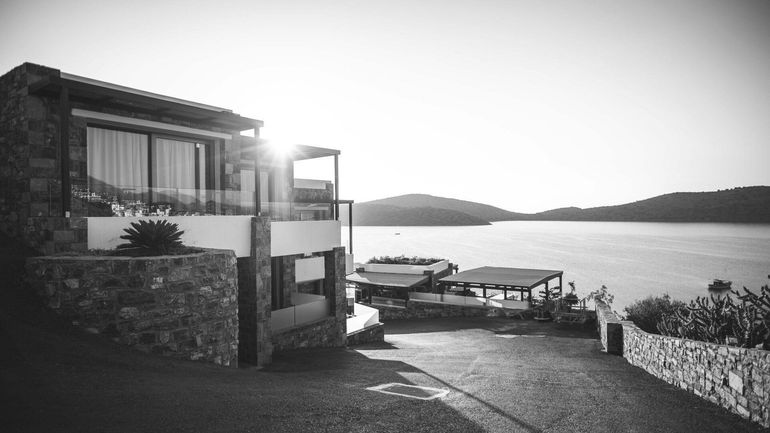 A black and white photo of a house next to a body of water