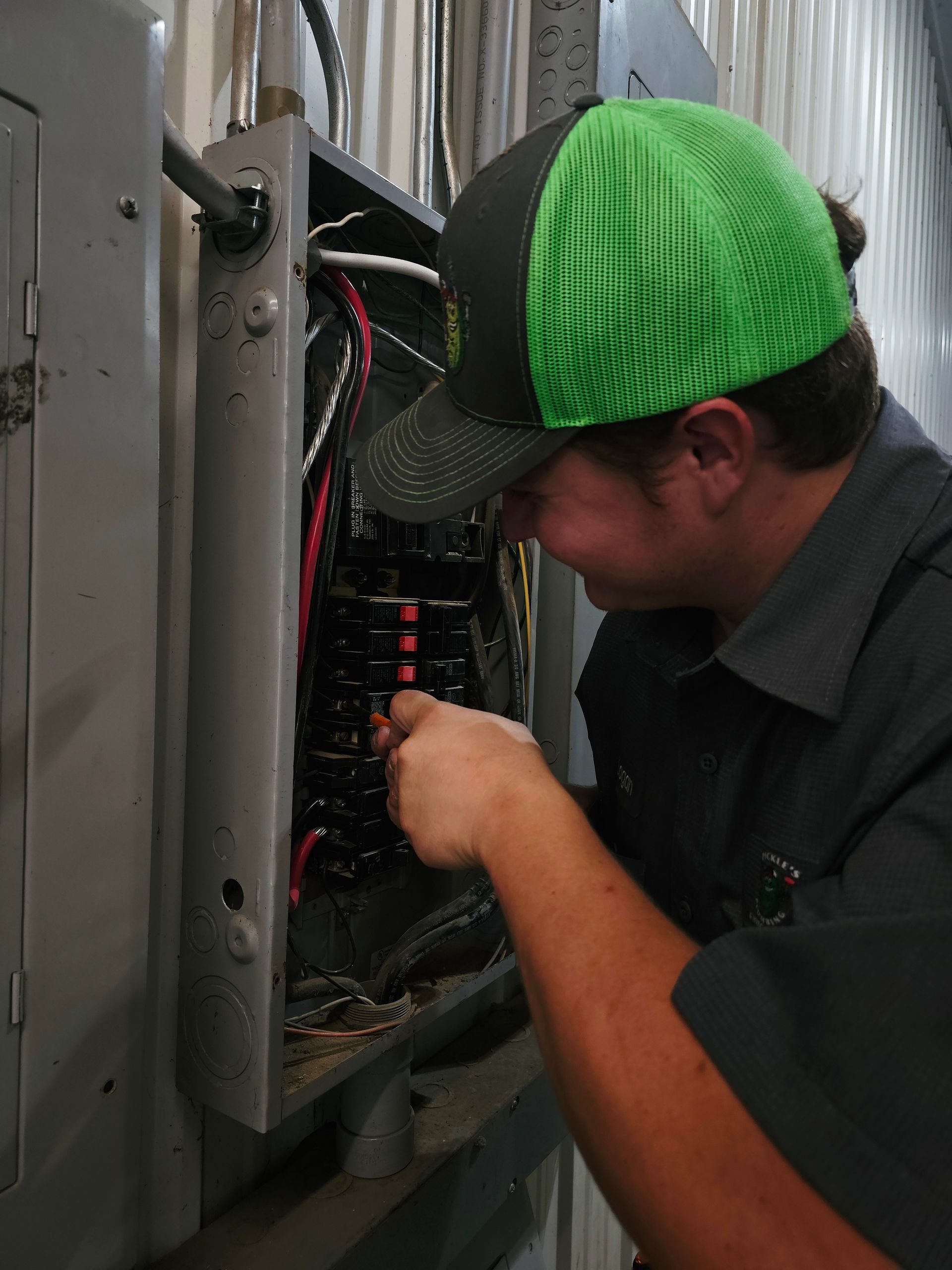 A man wearing a green hat is working on an electrical box