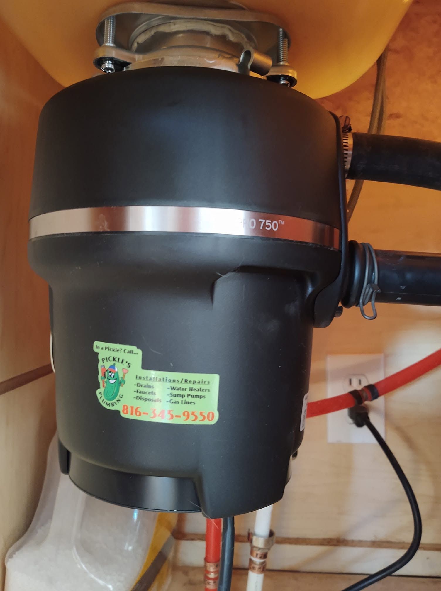 A black garbage disposal under a sink with a sticker on it